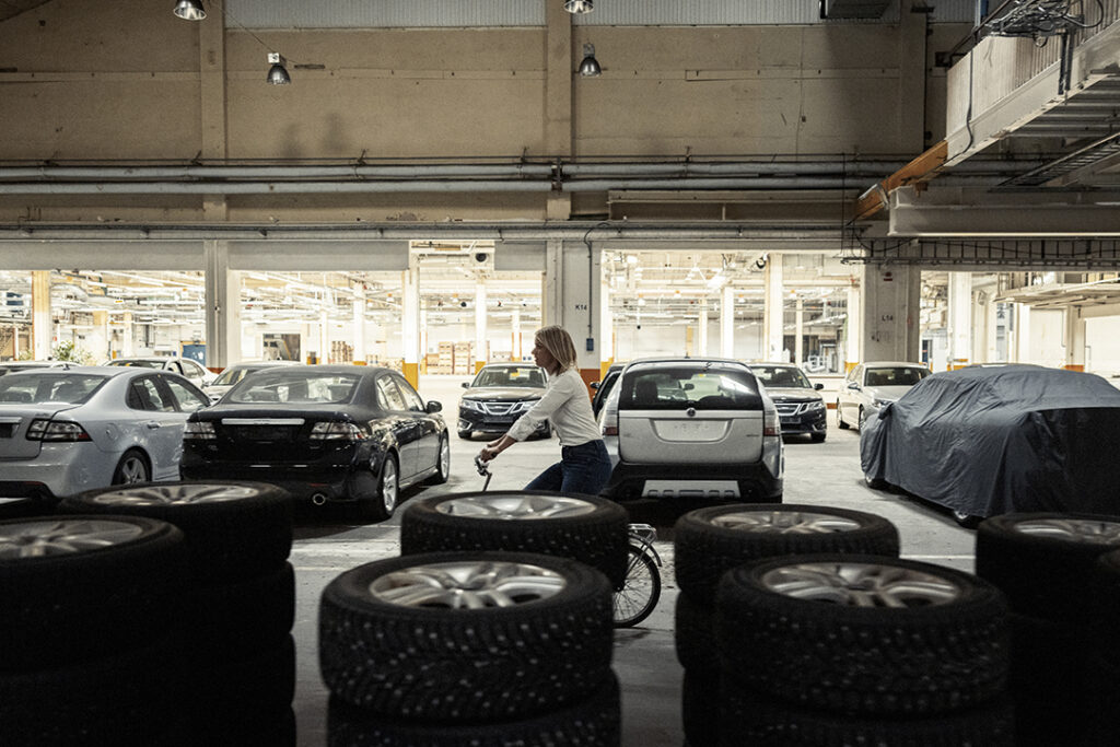 Nina Selander i en öde fabriksbyggnad med saab-bilar