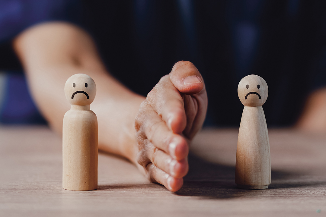 A person is holding two wooden figures with bad mood on face. Concept of soft skills and conflict resolution